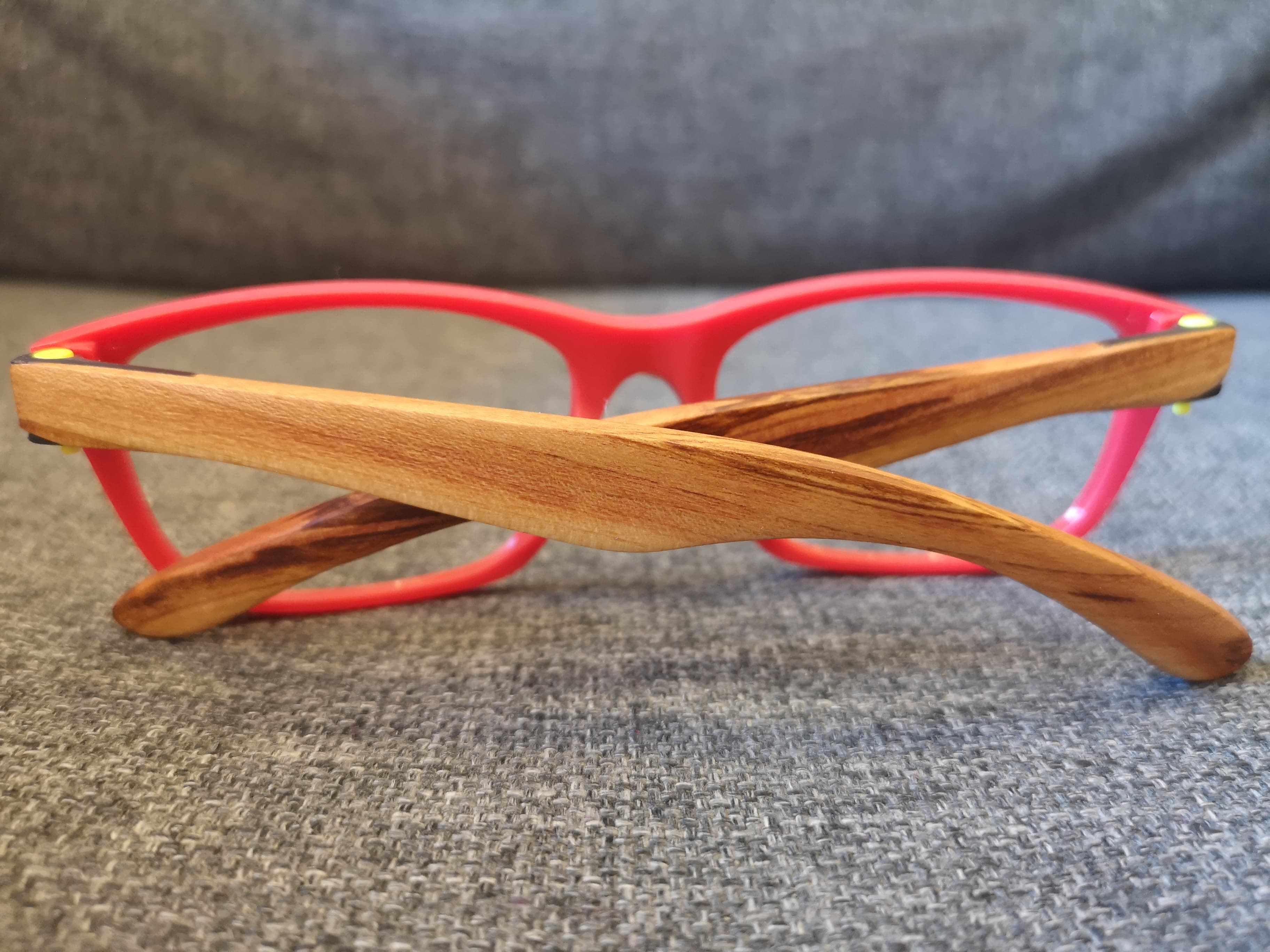 Top view of red eyeglass frames with naturally striped olive wood temples