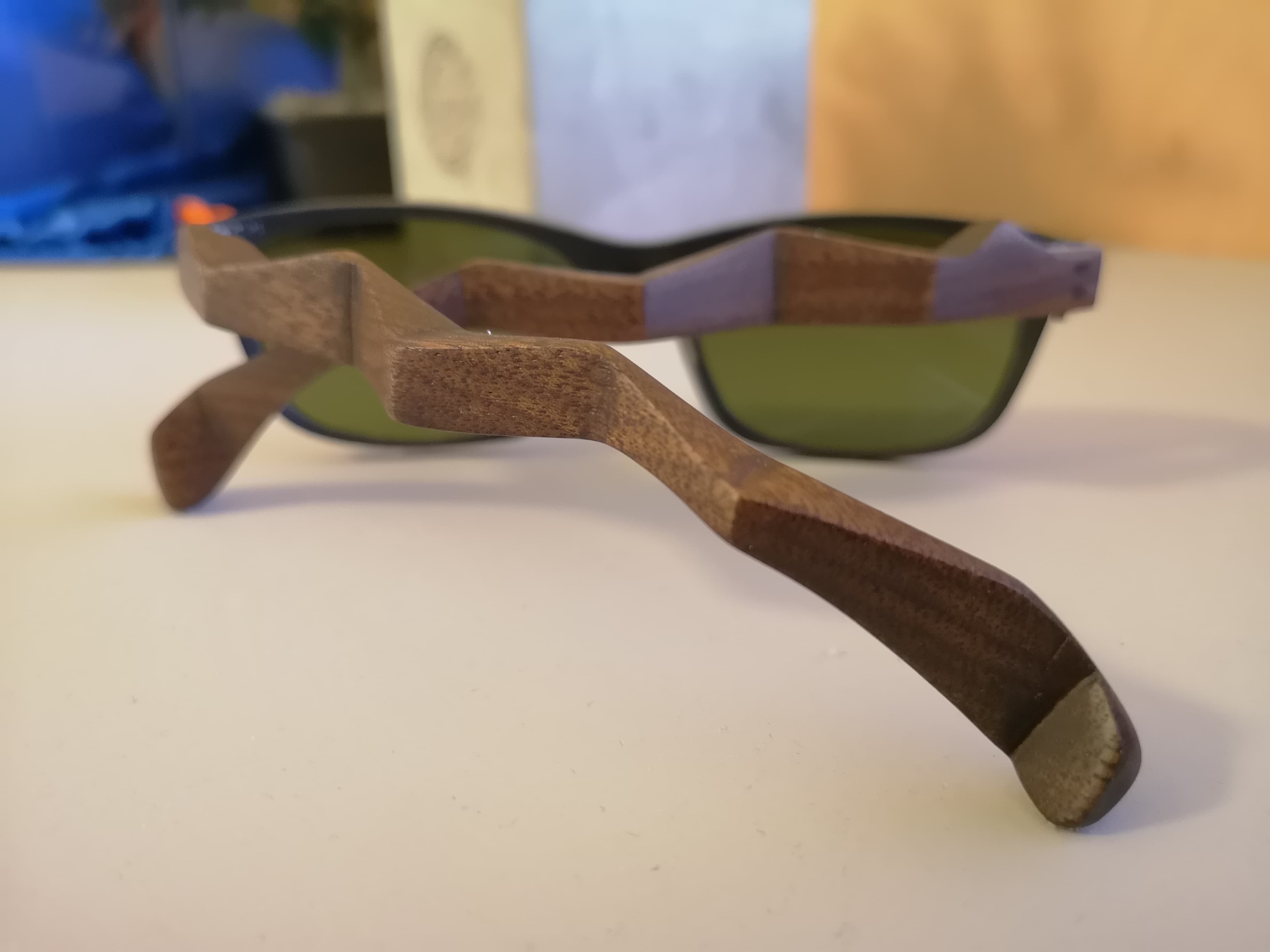 Angled overhead view of black sunglasses with carved wave walnut temples