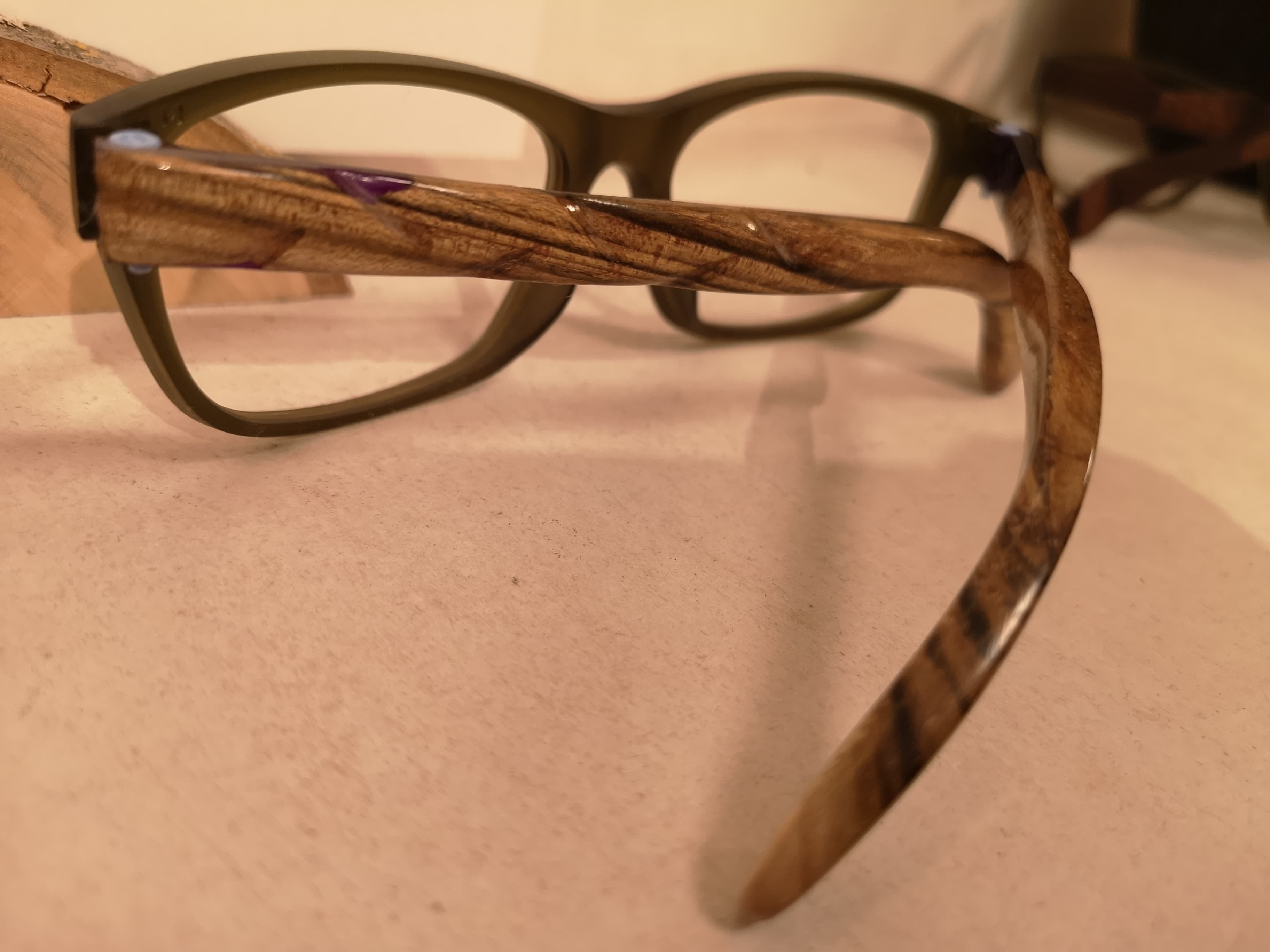 Side view of olive eyeglasses with walnut temples and purple diamond accents