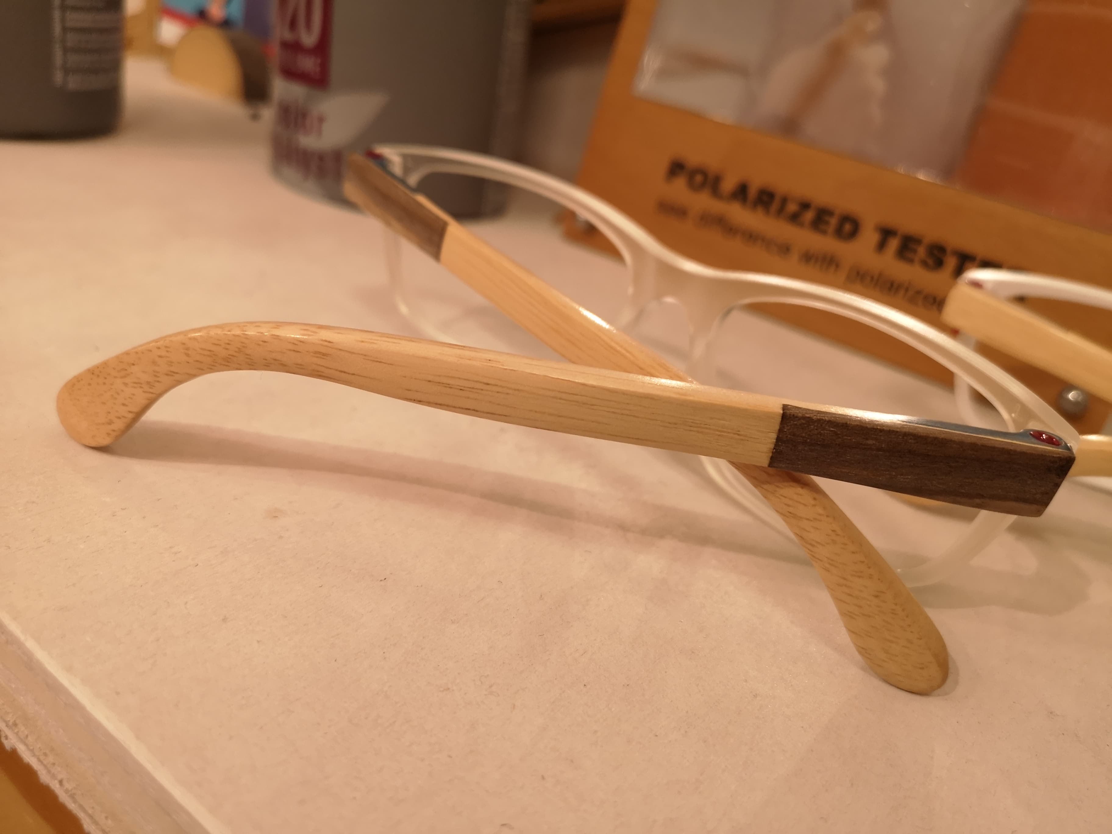 Clear eyeglass frames with two-tone beech and walnut wood temples showing the pale-to-dark contrast join