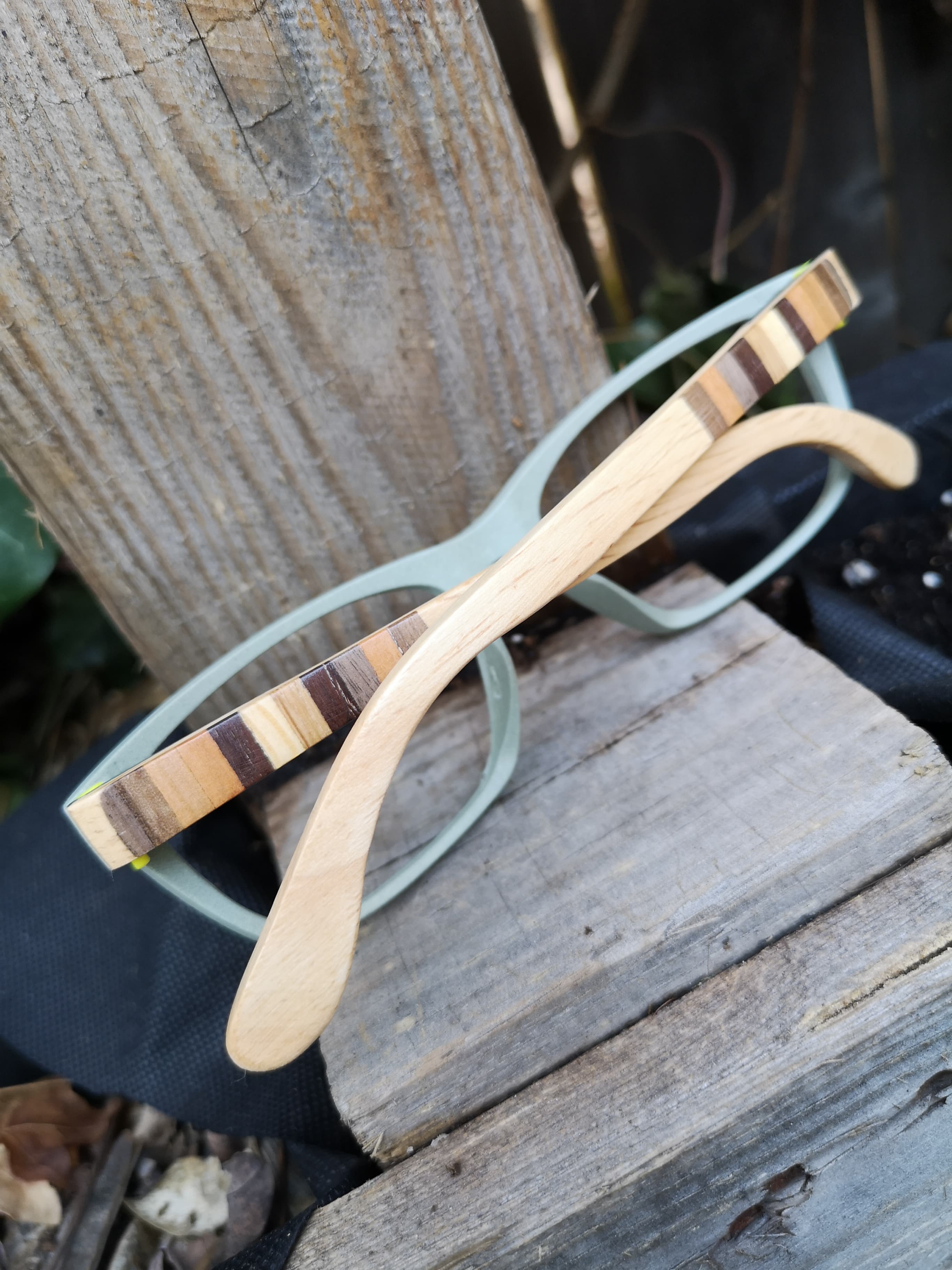 Portrait view of sage green frames with maple stripe-inlay temples