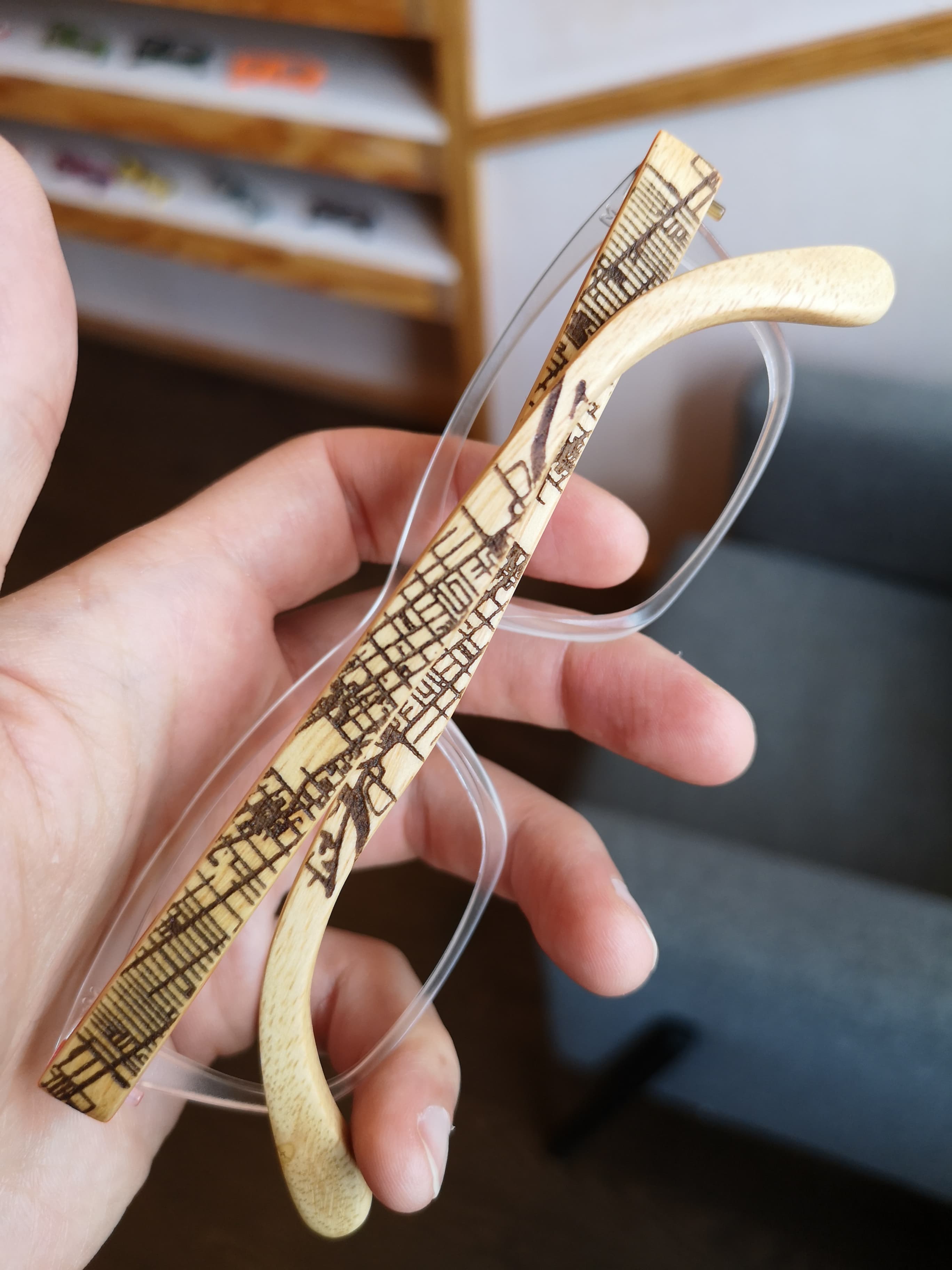 Clear eyeglasses with maple temples laser-engraved with a detailed topographic map pattern