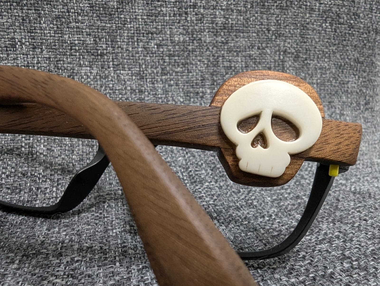 Front view of black upcycled material eyeglasses with walnut wood temples and carved skull medallions