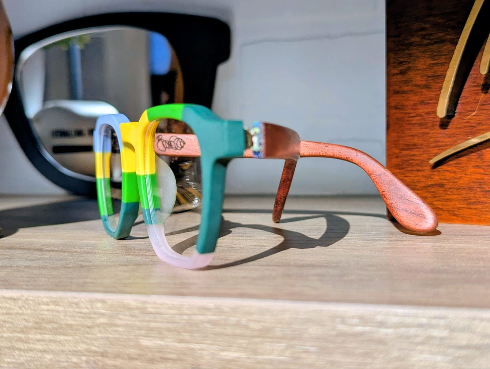 Color-block upcycled material frames with mahogany wood temples, folded with the temples crossed