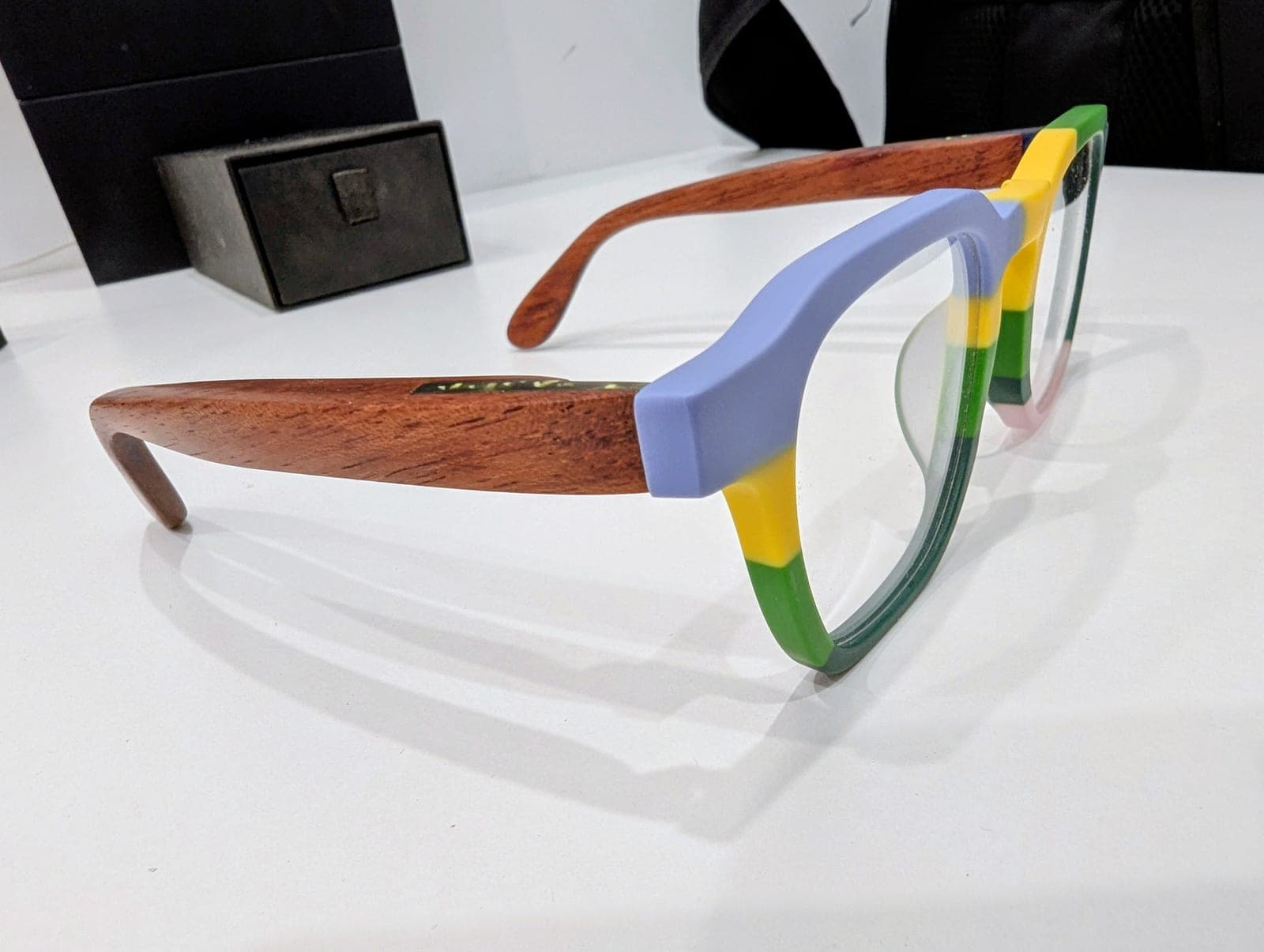 Detail of color-block upcycled material frames in blue, yellow, and green paired with reddish mahogany wood temples