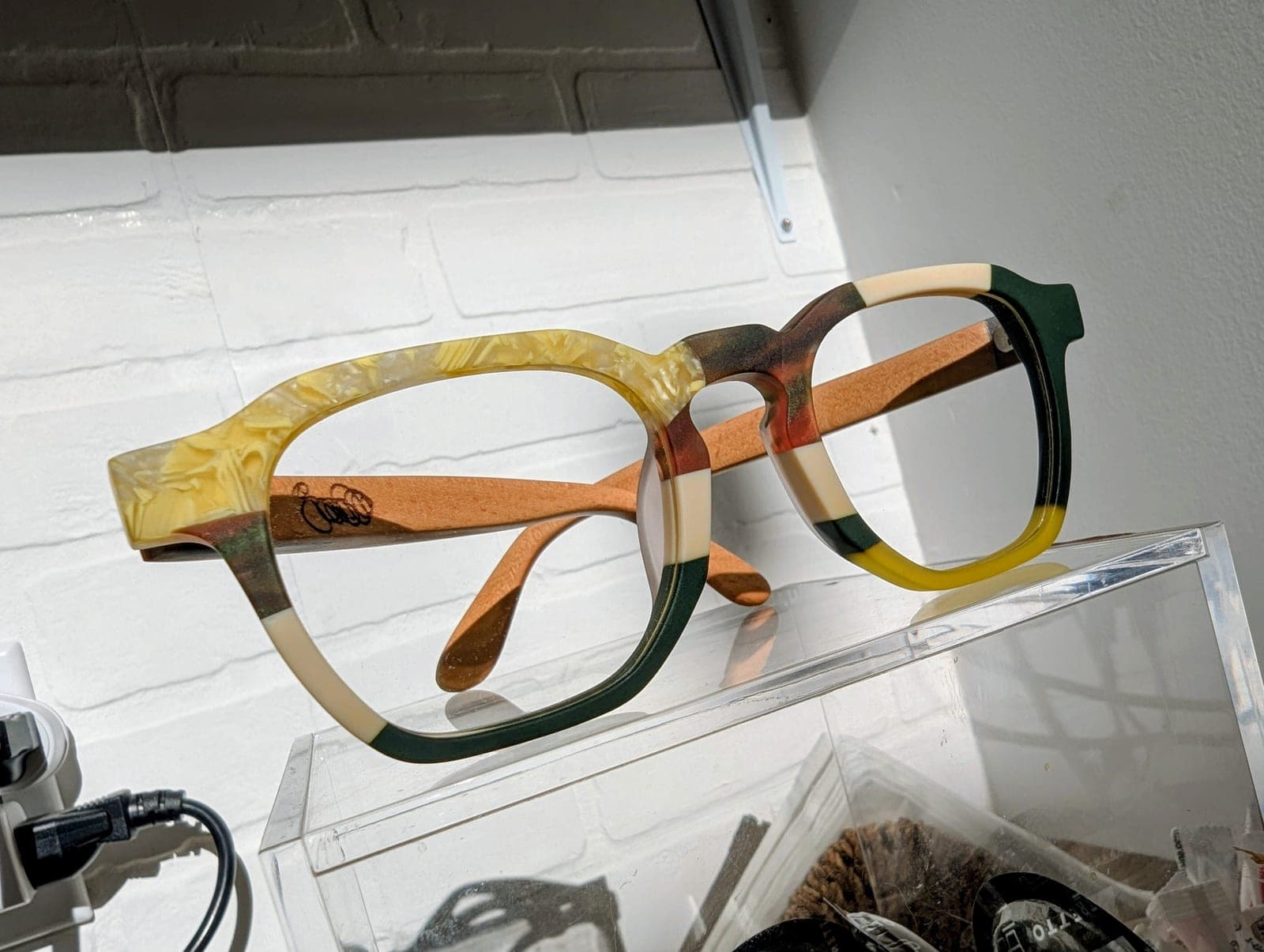 Tortoiseshell-pattern upcycled material eyeglass frames paired with light maple wood temples, engraved with a small logo