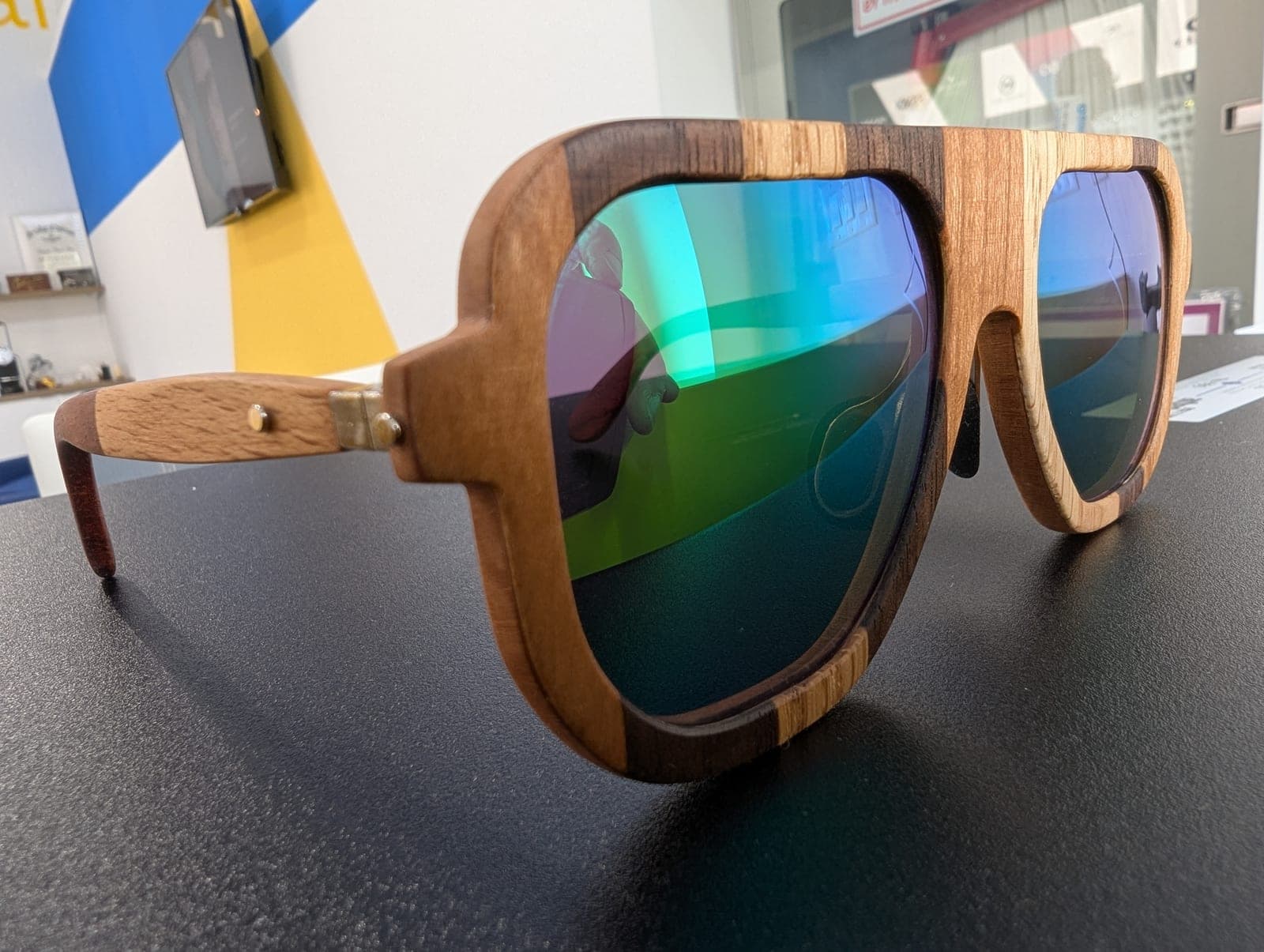 Two-tone wood aviator sunglasses combining light oak and dark walnut, with blue-green mirrored lenses