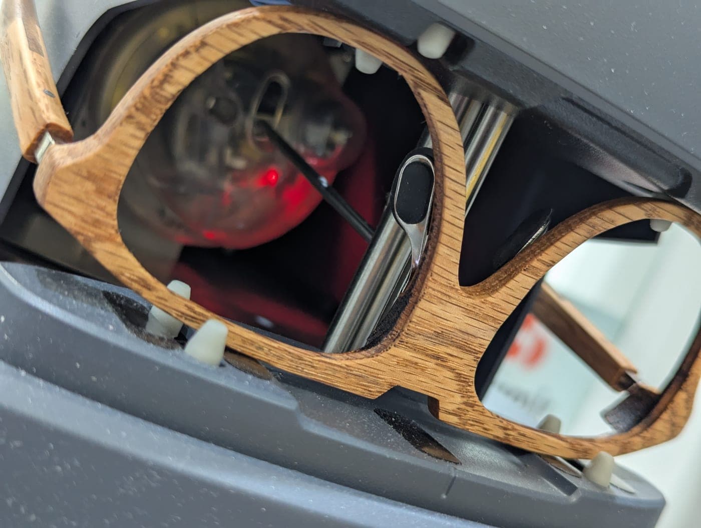 Macro shot of golden oak wood-framed glasses being checked on optical equipment in an eye clinic