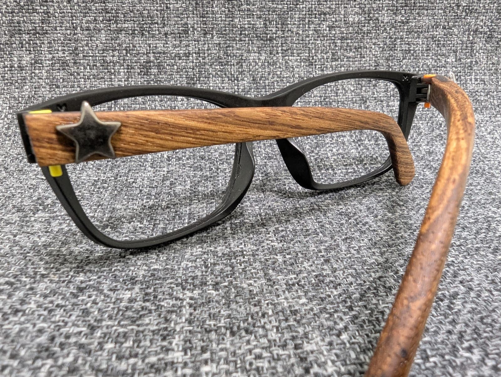Angled view of golden oak wood temples with star stud details on black upcycled material frames