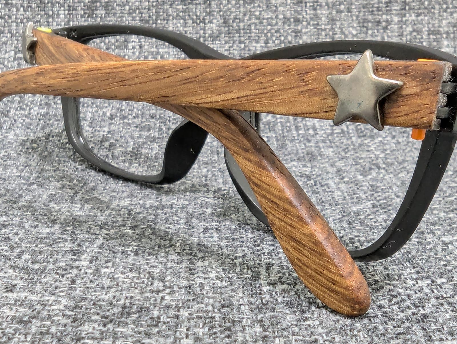 Close-up of a golden oak wood temple with a metal star stud on black upcycled material frames