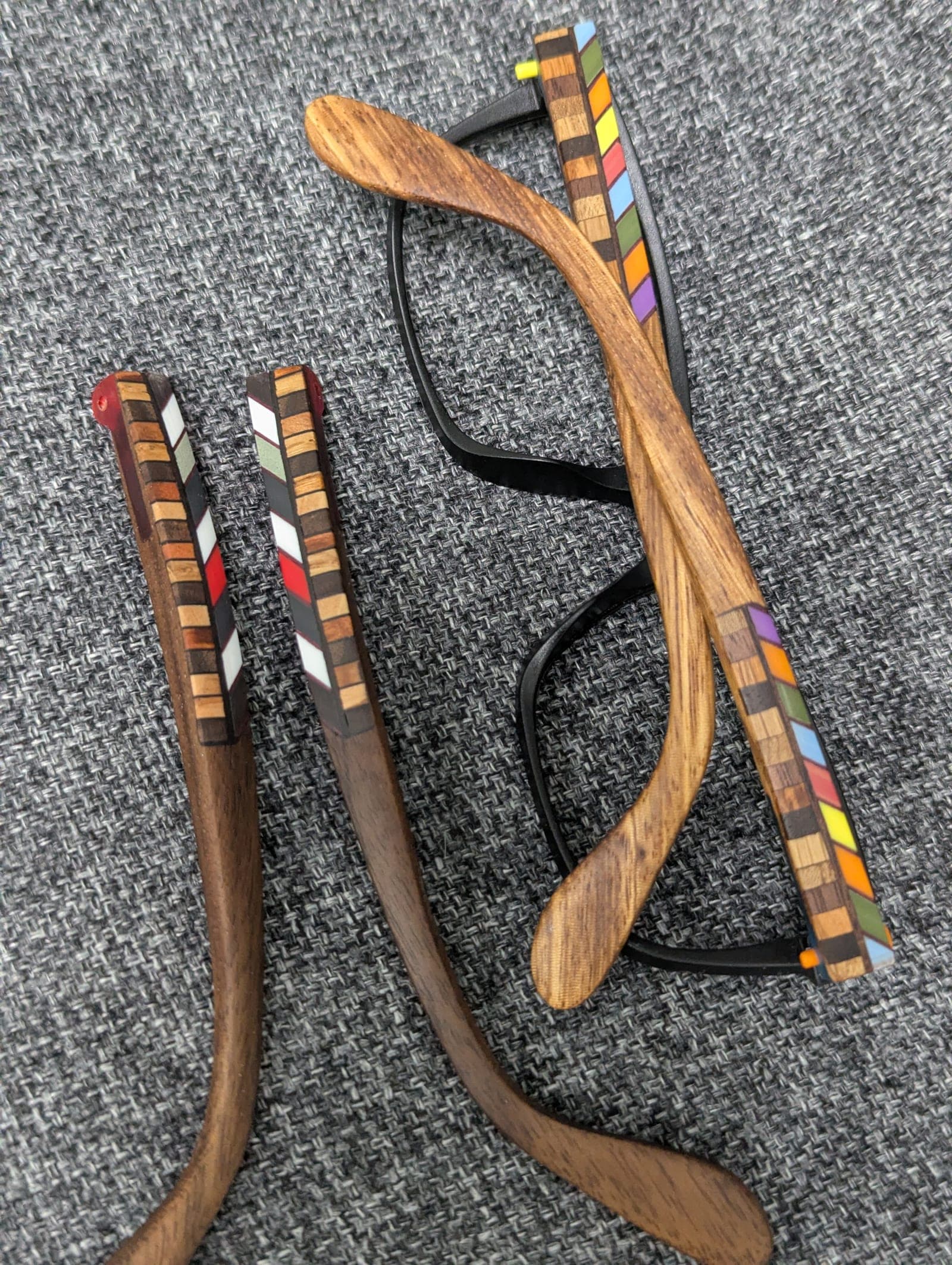 Side view of walnut wood temples with a colorful checkerboard mosaic inlay on black frames