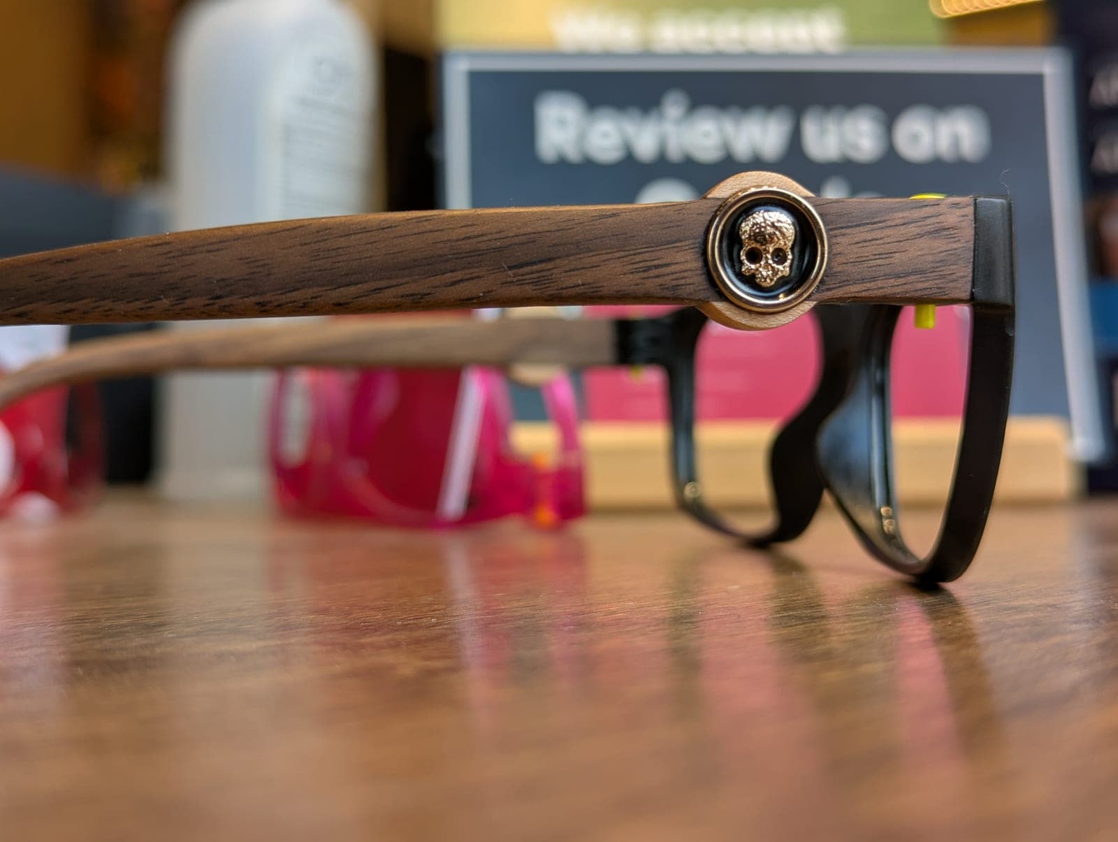 Side view of walnut wood temples with a small carved skull medallion on black upcycled material frames