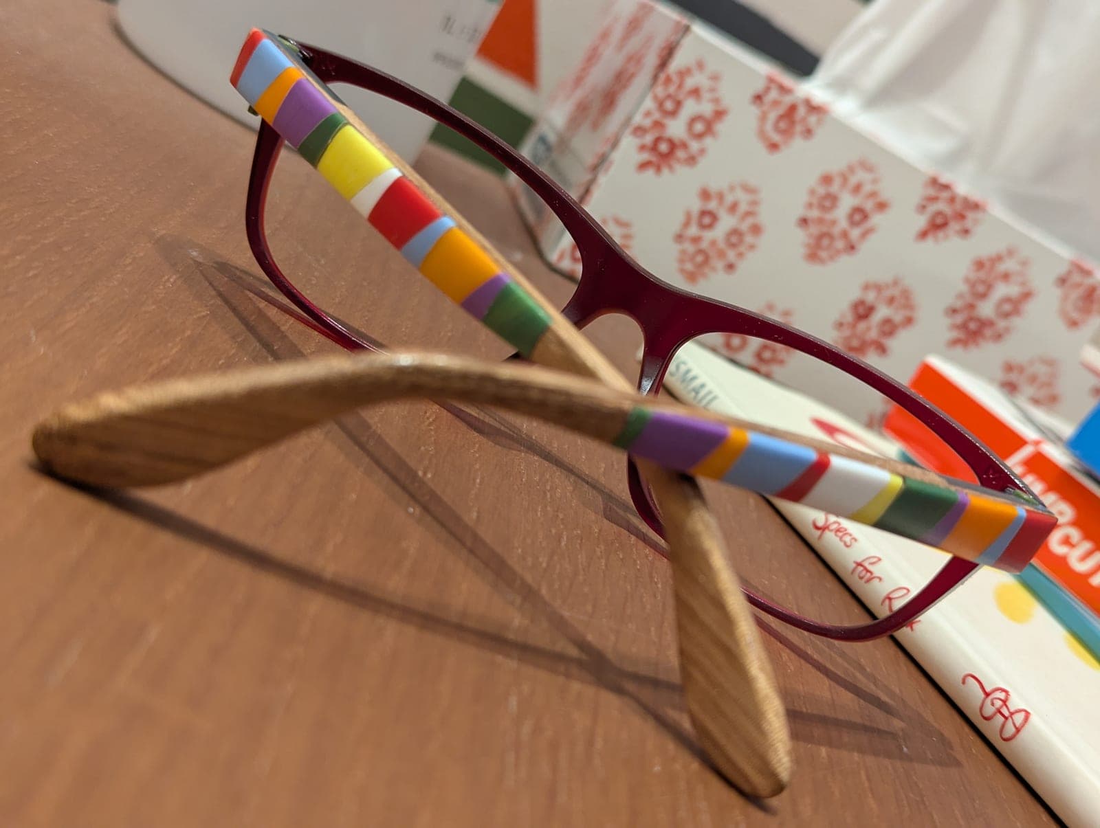 Clear upcycled material frames with striped oak and beech wood temples, folded with temples crossed