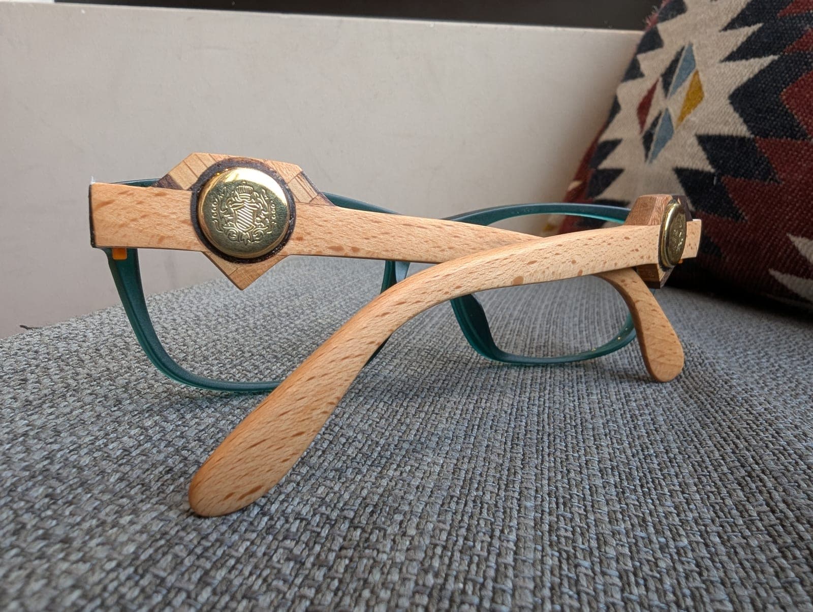 Angled view of teal upcycled material frames with maple wood temples and brass medallions