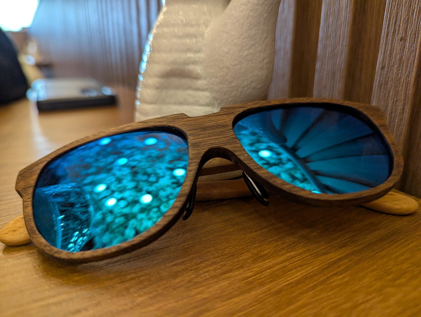 Close-up of wood-framed aviator sunglasses with blue mirrored lenses, showing the wood grain detail
